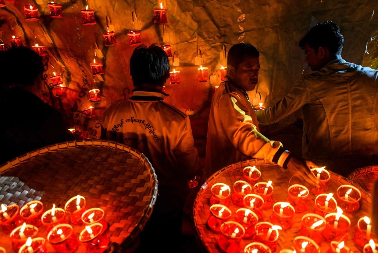 This photo taken on November 6, 2022 shows revellers preparing lanterns to attach to hot-air balloons during the Tazaungdaing Lighting Festival at Pyin Oo Lwin Township in Mandalay. (Photo by AFP)